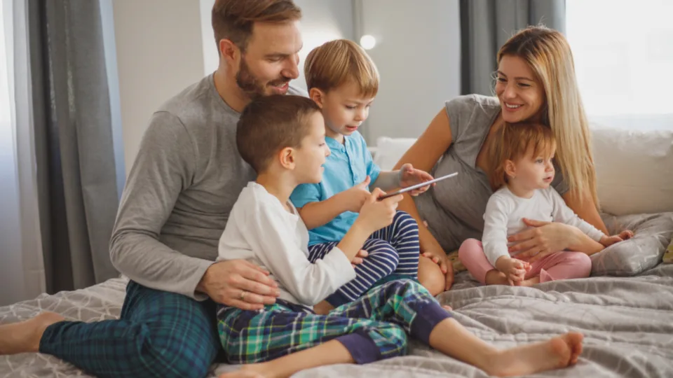 Familia reunida en la cama mirando juntos una tableta