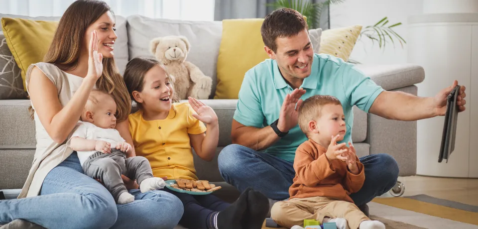 Familia sonriendo en la sala mientras usa una tableta